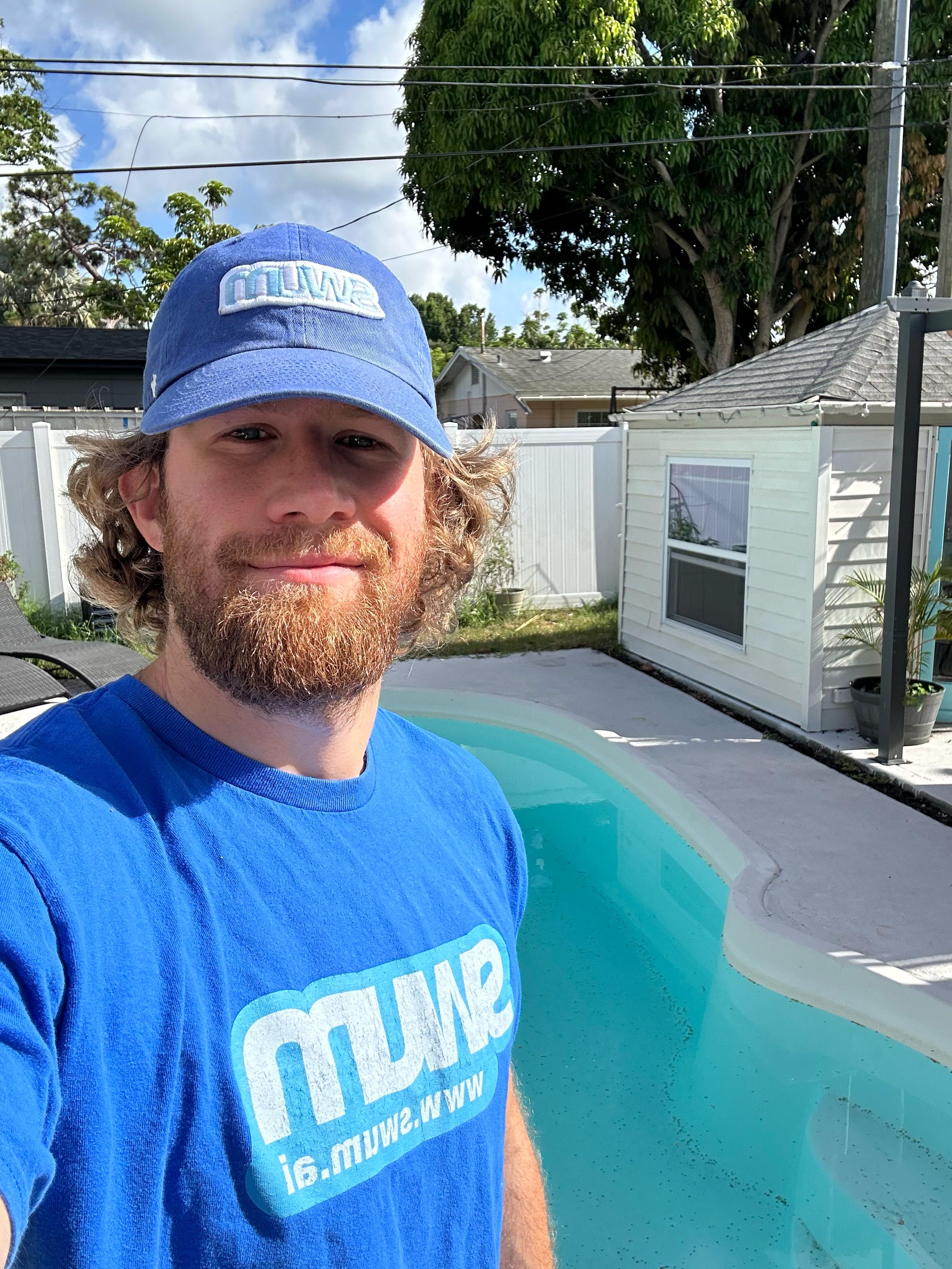 Swum founder Ben Gorski beside a swimming pool wearing a Swum shirt and hat